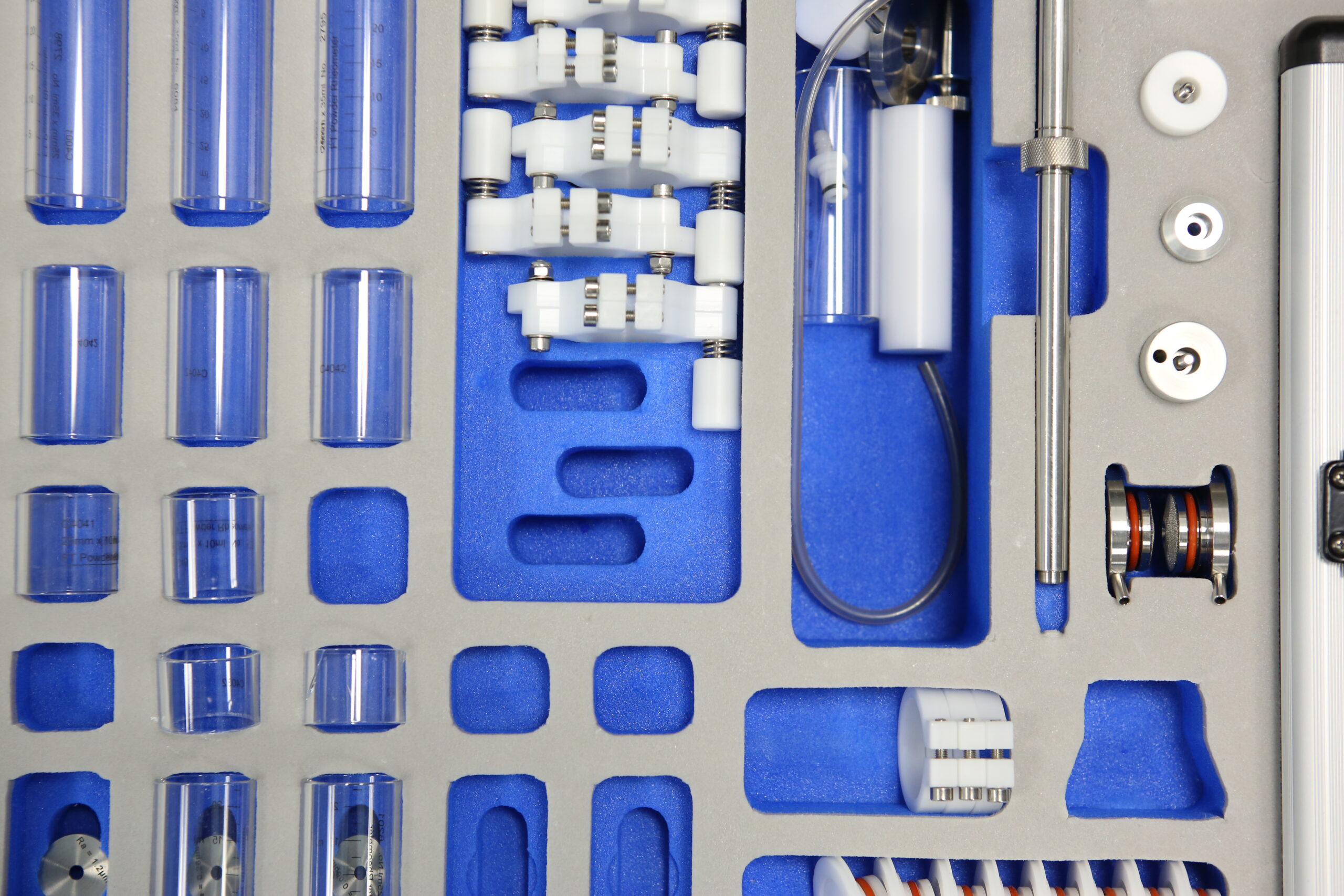 Grey case packed with white plastic and clear glass test parts for OINDP development services at Nanopharm.