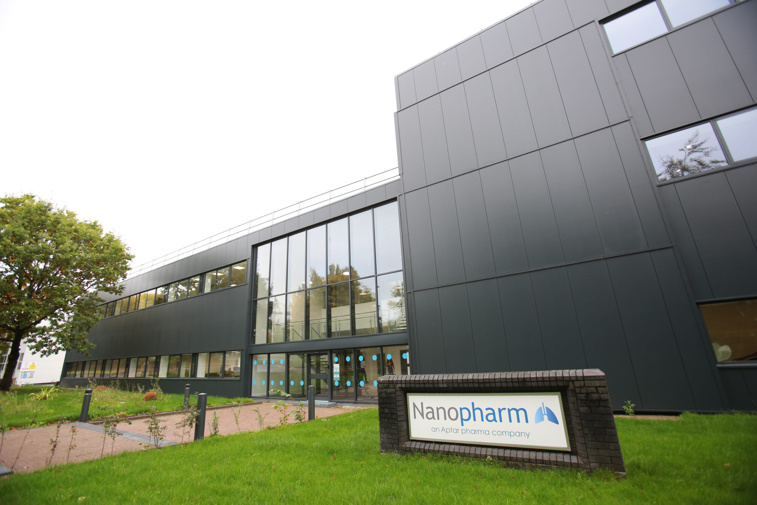 Exterior view of Nanopharm R&D CRO facility with black siding and rows of windows with brick pathway to front door.