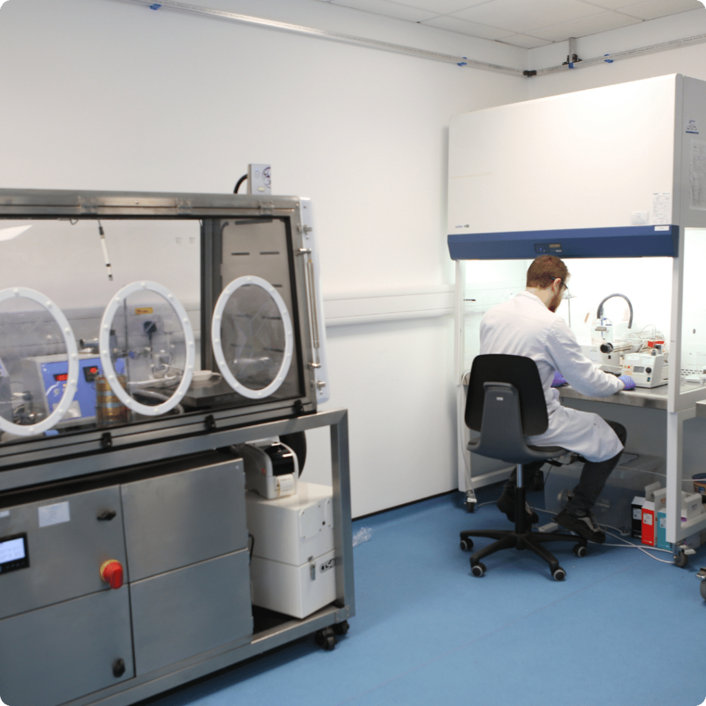 Nanopharm scientists seated in lab coat with a beard performs cGMP analytical services in a hood for OINDP clinical products.